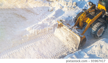 Big orange tractor removes snow from the road and clears the sidewalk 93967417