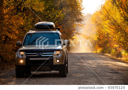 Mitsubishi Pajero on scenic autumn road in the forest 93970120
