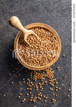 Uncooked buckwheat grain in bowl on black table. Top view. Uncooked buckwheat grain in bowl on black table. Top view. 93970485