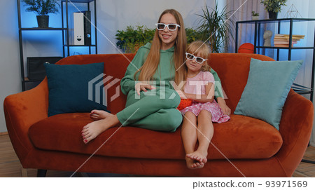 Girls friends siblings watching favorite tv show movie and eating popcorn, sitting on home sofa Girls friends siblings watching favorite tv show movie and eating popcorn, sitting on home sofa 93971569