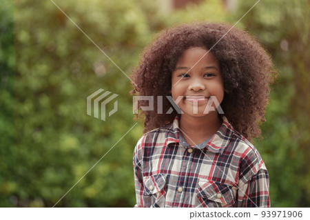 African American kid girl is smiling in the garden or outdoors. African American kid girl is smiling in the garden or outdoors. 93971906