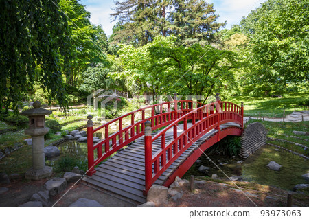 Traditional red wooden bridge on a japanese garden pond Traditional red wooden bridge on a japanese garden pond 93973063