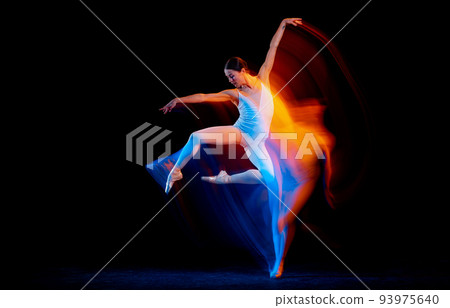 Young and graceful female ballet dancer dancing over dark background in mixed neon light. Art, motion, action, flexibility, inspiration concept. 93975640