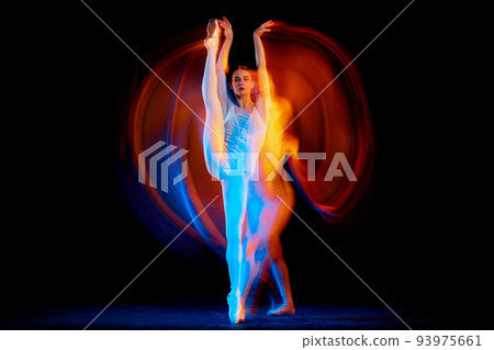Dynamic portrait of tender slim girl, female ballet dancer in art performance isolated over black background in mixed bright neon light. 93975661