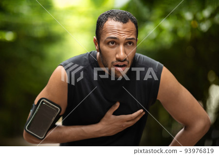 Black sportsman with heart pain, training outdoors Black sportsman with heart pain, training outdoors 93976819