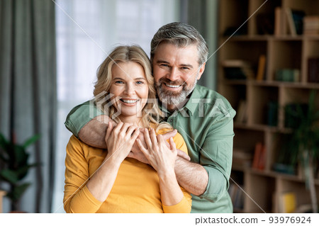 Portrait Of Loving Middle Aged Spouses Embracing And Smiling At Camera Portrait Of Loving Middle Aged Spouses Embracing And Smiling At Camera 93976924