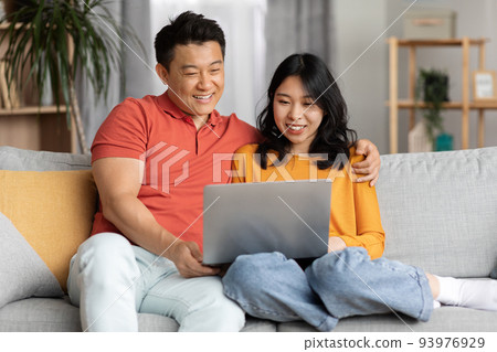 Asian lovers watching movie on Internet, using laptop 93976929