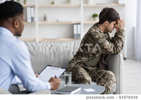 Upset young man veteran attending psychotherapist at clinic Upset young man veteran attending psychotherapist at clinic 93976939