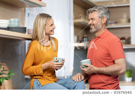 Happy lovers drinking cofee and chatting at kitchen Happy lovers drinking cofee and chatting at kitchen 93976940