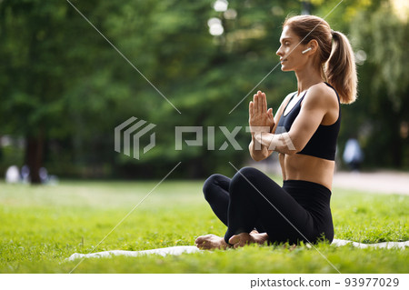 Peaceful blonde woman meditating at public park Peaceful blonde woman meditating at public park 93977029