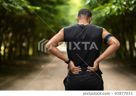 Back view of sportsman touching sore zone on his back 93977031