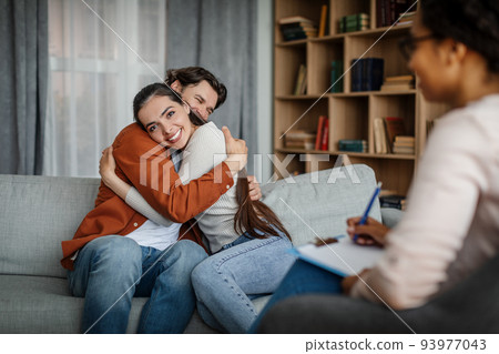 Glad millennial european male and female hugging at meeting with psychologist in office Glad millennial european male and female hugging at meeting with psychologist in office 93977043