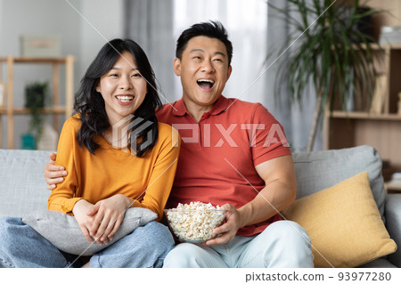 Cheerfy asian man and woman watching TV at home 93977280