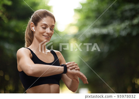 Happy young sporty woman set her fitness tracker 93978032