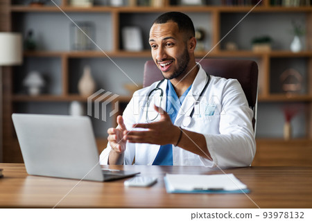 Handsome black doctor working online, having video chat at clinic Handsome black doctor working online, having video chat at clinic 93978132