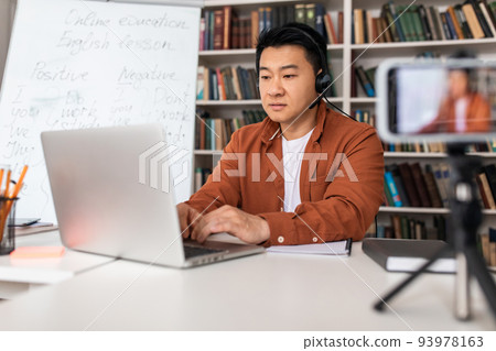 Japanese Teacher Using Laptop Wearing Headset Having Online Lecture Indoor Japanese Teacher Using Laptop Wearing Headset Having Online Lecture Indoor 93978163
