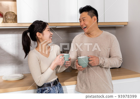 Happy asian couple enjoying morning coffee at home Happy asian couple enjoying morning coffee at home 93978399