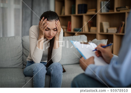 Despaired sad young caucasian lady suffering from mental problems listens to male doctor in office Despaired sad young caucasian lady suffering from mental problems listens to male doctor in office 93978910
