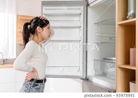 Overwhelmed young korean lady checking her fridge Overwhelmed young korean lady checking her fridge 93978991