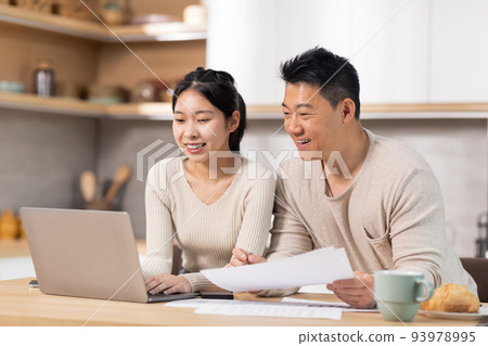 Cheerful asian couple paying bills on Internet, using laptop 93978995