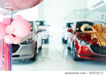 Pink balloons on blur car parked in luxury showroom. New car parked in modern showroom. Car dealership office. Automobile leasing and insurance concept. Auto leasing business. Electric vehicle dealer. 93979171