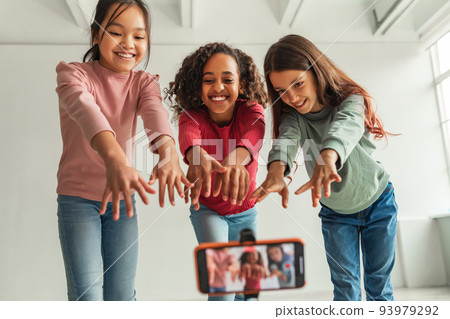 Three Multiethnic Blogger Girls Posing Making Video On Cellphone Indoors 93979292