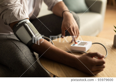 Closeup of young black man checking blood pressure, using modern tonometer at home 93979600