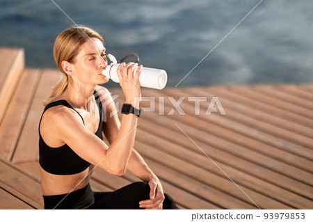 Tired Sporty Middle Aged Woman Drinking Water From Bottle After Training Outdoors 93979853