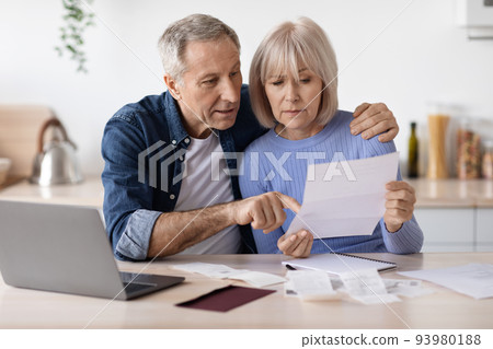 Serious pensioners sittting in front of computer, reading letter 93980188