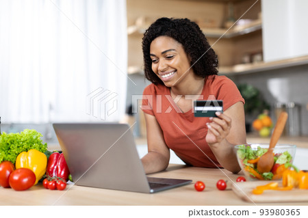 Satisfied young african american lady with laptop and credit card buy purchases remote, enjoy huge sale 93980365