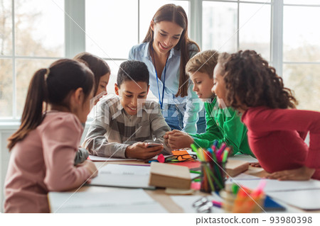 Multiethnic School Kids And Teacher Using Smartphone In Modern Classroom 93980398