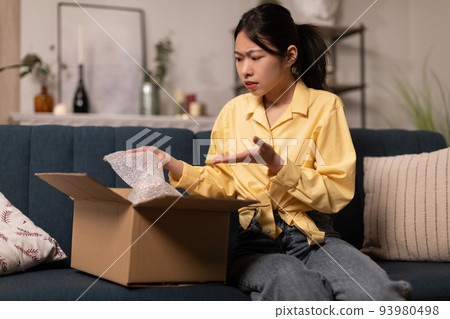 Discontented Asian Lady Unpacking Cardboard Box With Bad Product Indoor 93980498