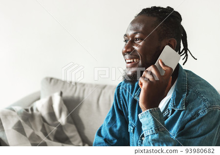 Cheerful African American Man Talking On Cellphone Sitting At Home 93980682