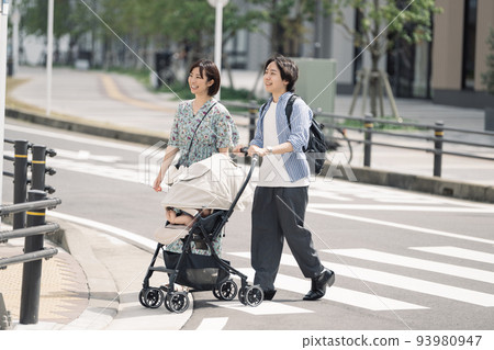 A couple raising children crossing a pedestrian crossing 93980947