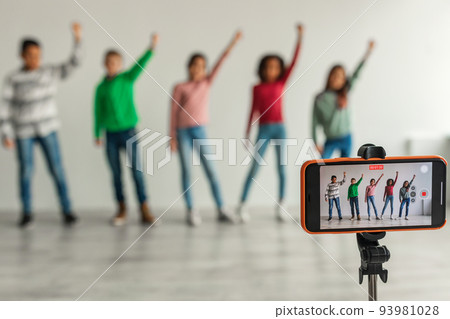 Group Of Kids Filming Video For Blog Via Smartphone Indoors Group Of Kids Filming Video For Blog Via Smartphone Indoors 93981028