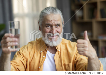 Happy grandfather holding glass of water and showing thumb up 93981047