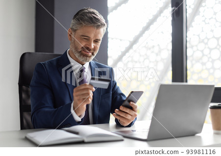 Online Banking. Middle Aged Businessman Using Smartphone And Credit Card In Office 93981116