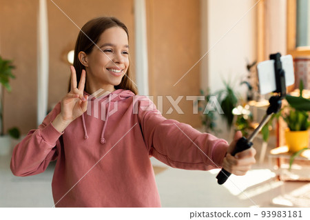 Blogging concept. Happy teen girl recording lifestyle blog talking to cellphone webcamera on tripod 93983181