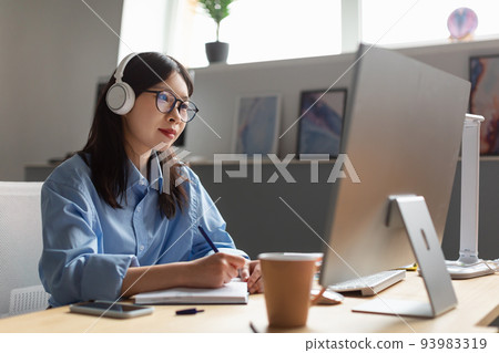 Asian Businesswoman Working On Computer And Taking Notes In Office Asian Businesswoman Working On Computer And Taking Notes In Office 93983319