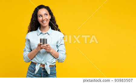Cheerful Arabic Woman Using Mobile Phone On Yellow Background, Panorama Cheerful Arabic Woman Using Mobile Phone On Yellow Background, Panorama 93983507