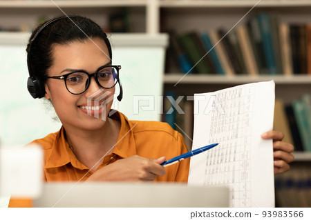 Happy mixed race woman having video conference on laptop, giving presentation or online class to students in library 93983566