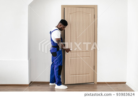 Black Repairman Installing Entry Door, Fixing Lock And Handle Indoor 93983624
