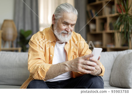 Happy senior man using smartphone at home 93983788