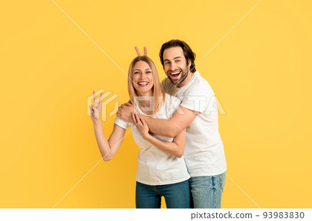 Cheerful funny millennial caucasian woman and man in white t-shirts have fun, show peace sign with hands 93983830