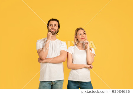 Pensive millennial caucasian male and woman in white t-shirts think and look up at empty space Pensive millennial caucasian male and woman in white t-shirts think and look up at empty space 93984626