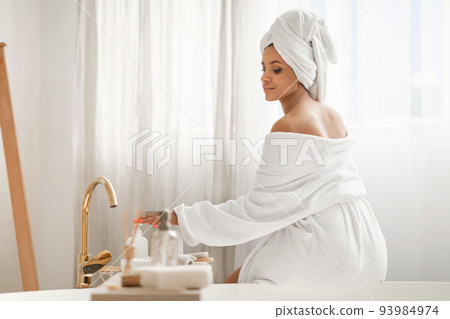Relaxed Woman Enjoying Bodycare Rituals Using Cosmetics Sitting In Bathroom Relaxed Woman Enjoying Bodycare Rituals Using Cosmetics Sitting In Bathroom 93984974