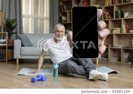 Sporty senior man showing cell phone with empty screen 93985184