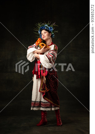 Art portrait of beautiful woman wearing traditional folk Ukrainian costume posing isolated over dark vintage background. Fashion, beauty, cultural heritage Art portrait of beautiful woman wearing traditional folk Ukrainian costume posing isolated over dark vintage background. Fashion, beauty, cultural heritage 93985272