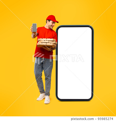 Deliveryman Near Huge Cellphone Holding Pizza Showing Phone In Studio Deliveryman Near Huge Cellphone Holding Pizza Showing Phone In Studio 93985274
