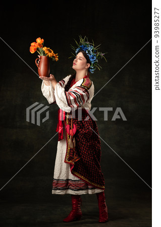 Art portrait of beautiful woman wearing traditional folk Ukrainian costume posing isolated over dark vintage background. Fashion, beauty, cultural heritage Art portrait of beautiful woman wearing traditional folk Ukrainian costume posing isolated over dark vintage background. Fashion, beauty, cultural heritage 93985277